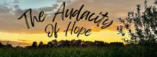 Image of Indiana sunset over cornfields with the words The Audicity to Hope written in the sky.